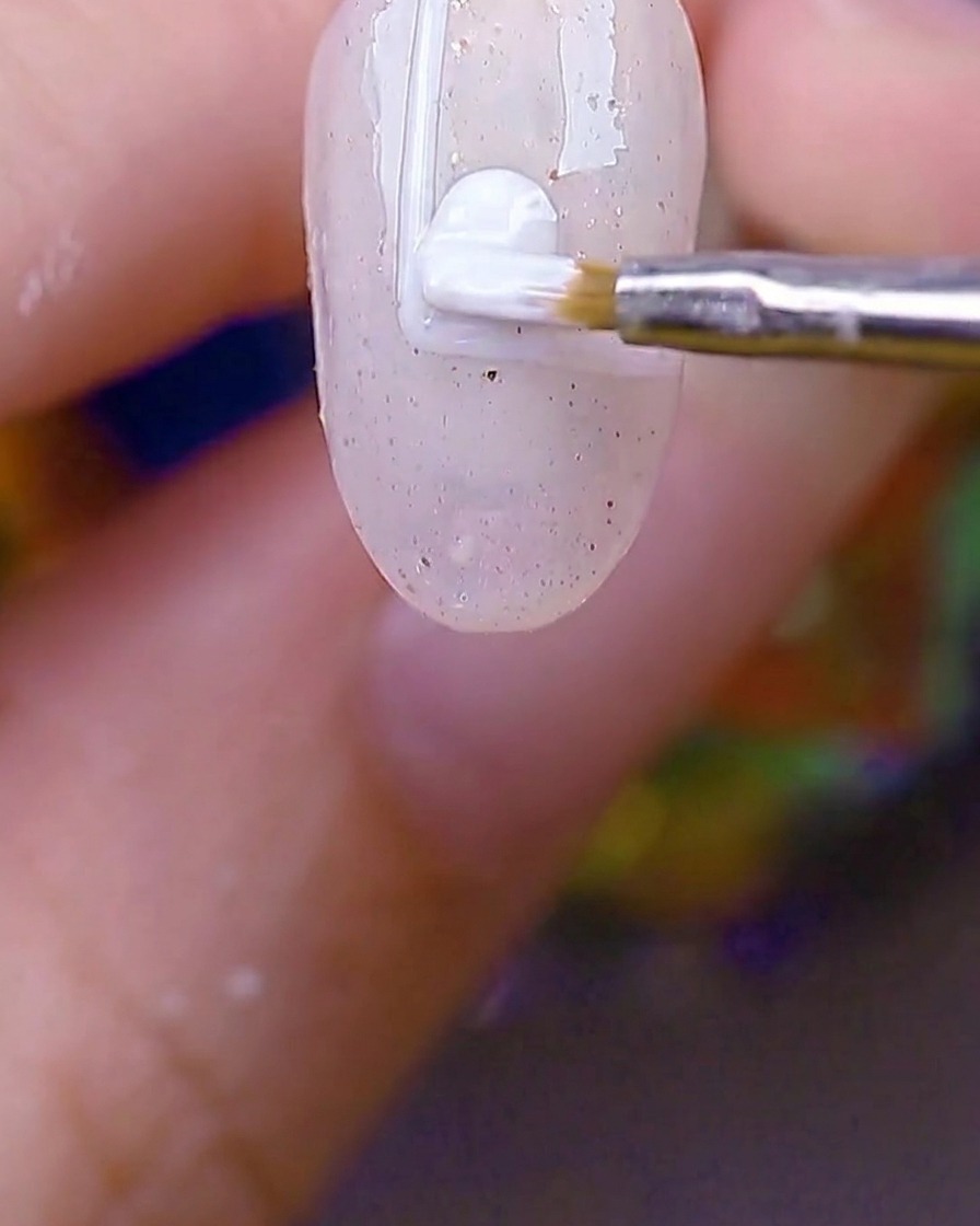 Un piccolo pennello tondo che riempie il rettangolo con bordo bianco sullunghia con gel bianco opaco.