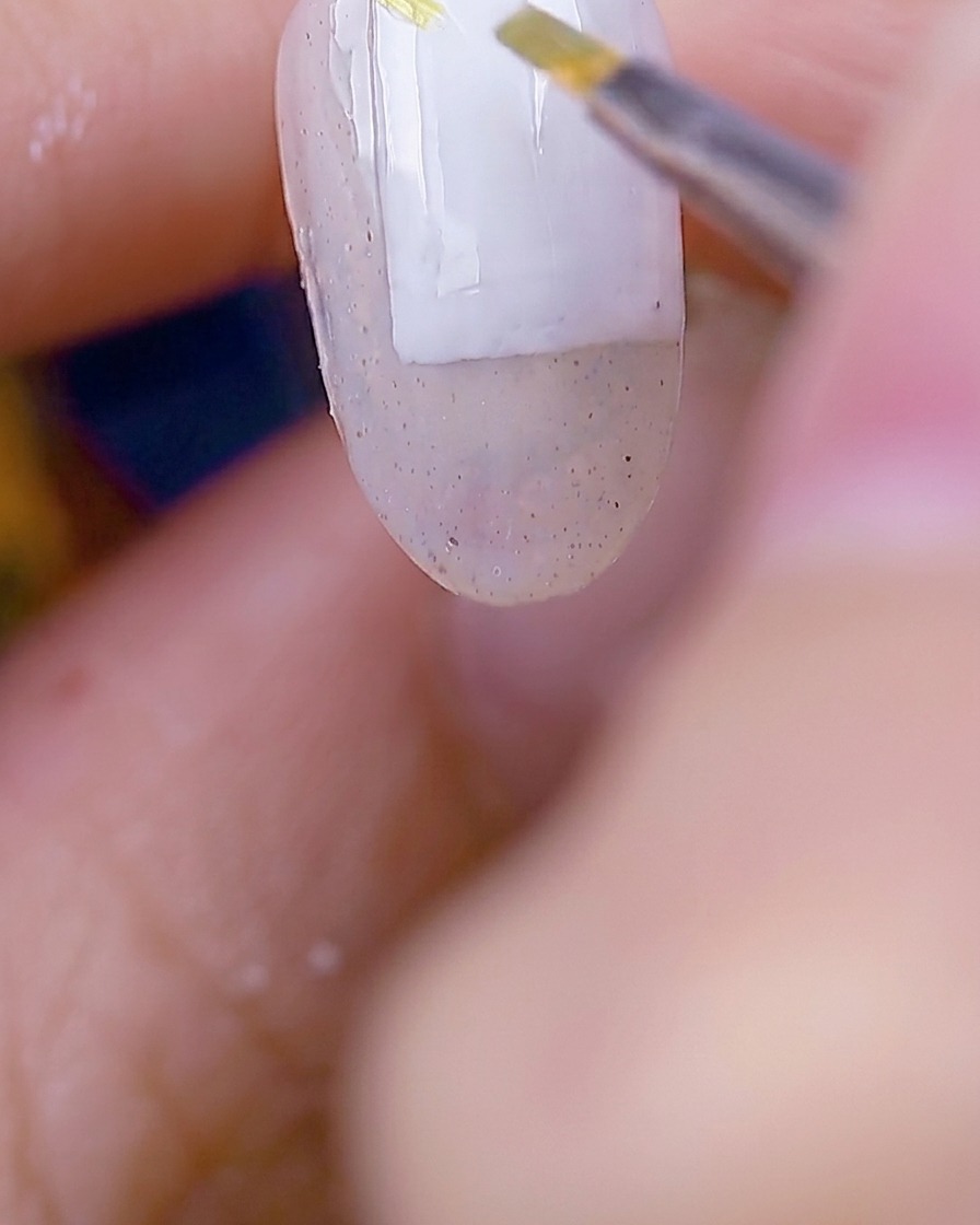 Un pennello che applica gel verde muschio per creare delicate forme di foglie sulla superficie dellunghia preparata.