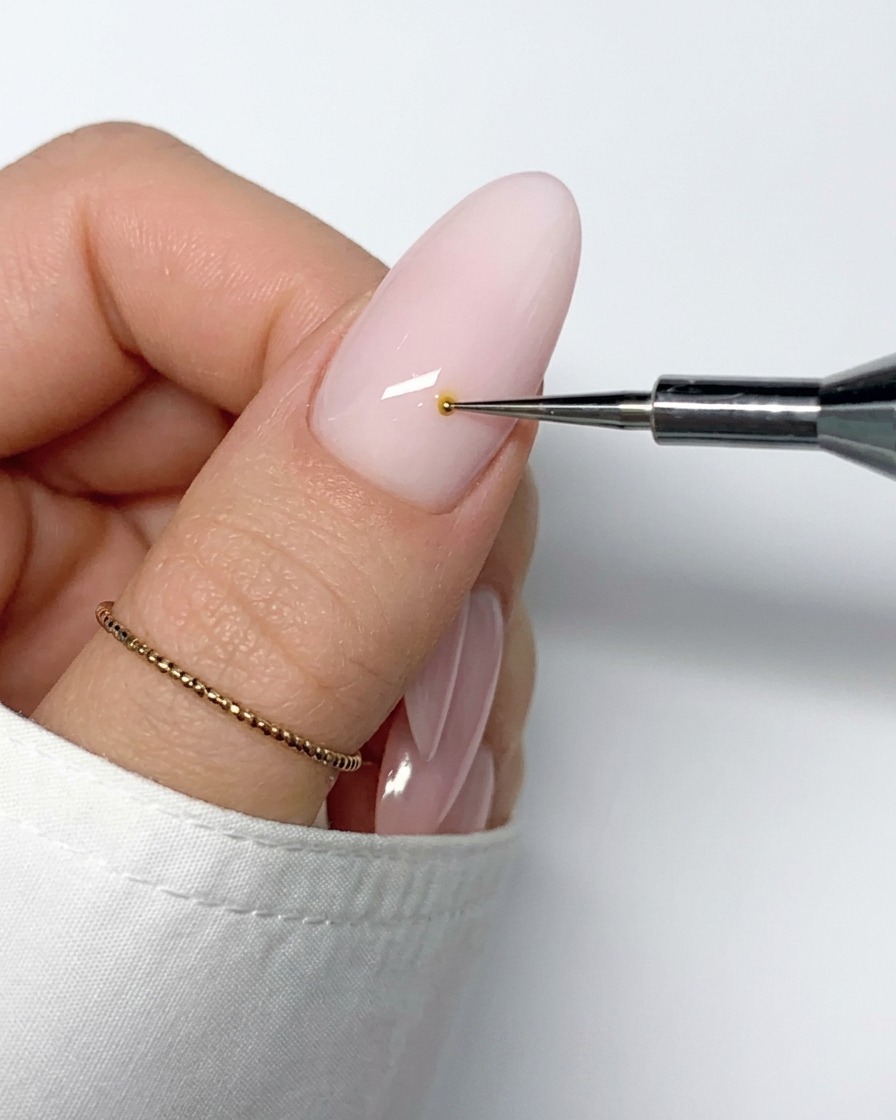 Un pennello sottile per nail art che tira una linea di smalto gel bianco verso lesterno dal centro giallo.