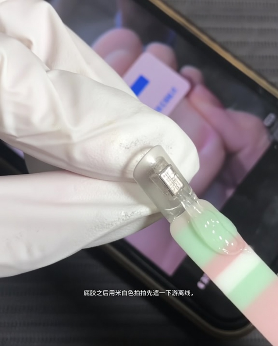 Un pennello applica gel bianco latte sulla punta di ununghia naturale.