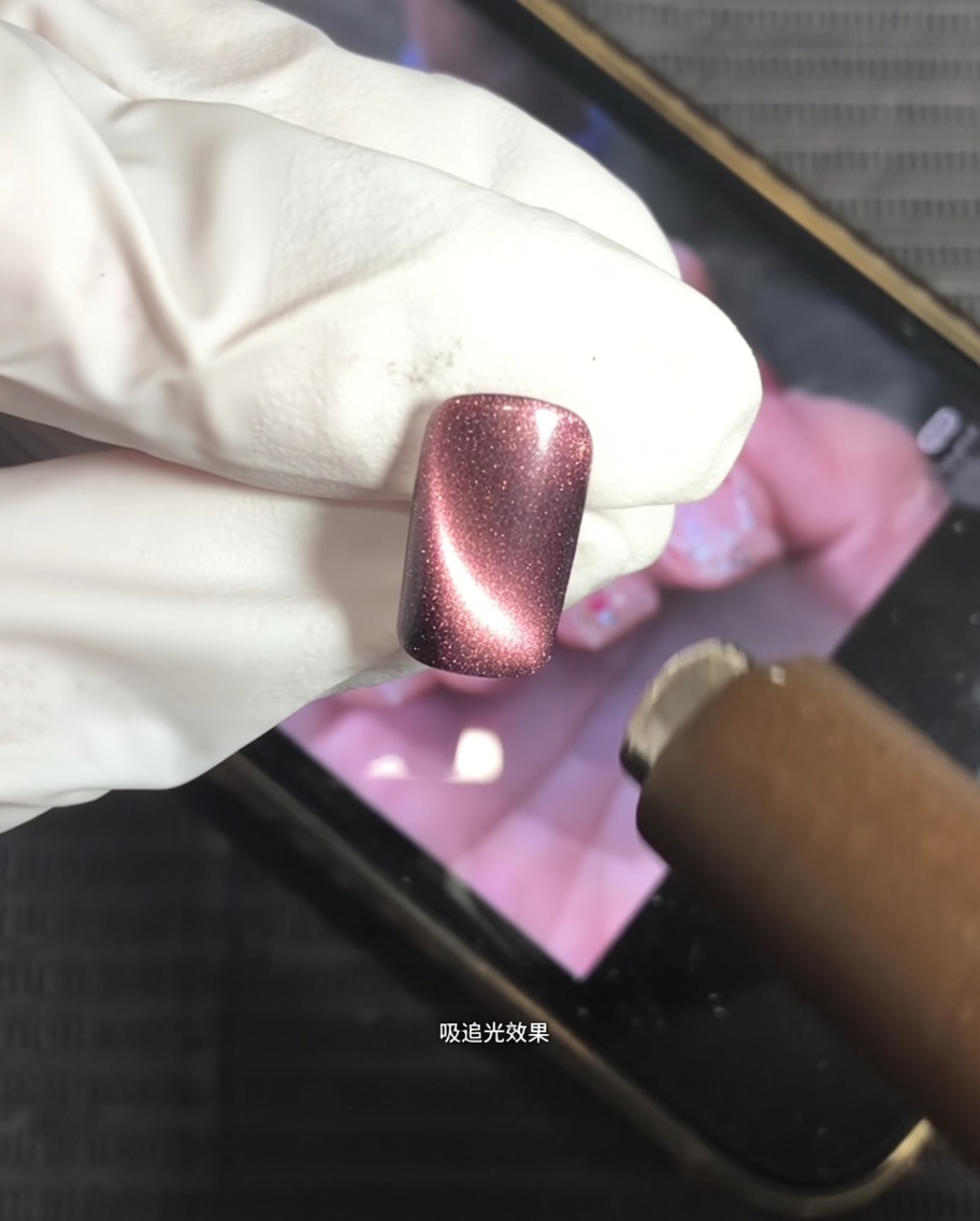 Un magnete viene tenuto sopra ununghia con gel cat-eye per creare un riflesso luminoso centrato.