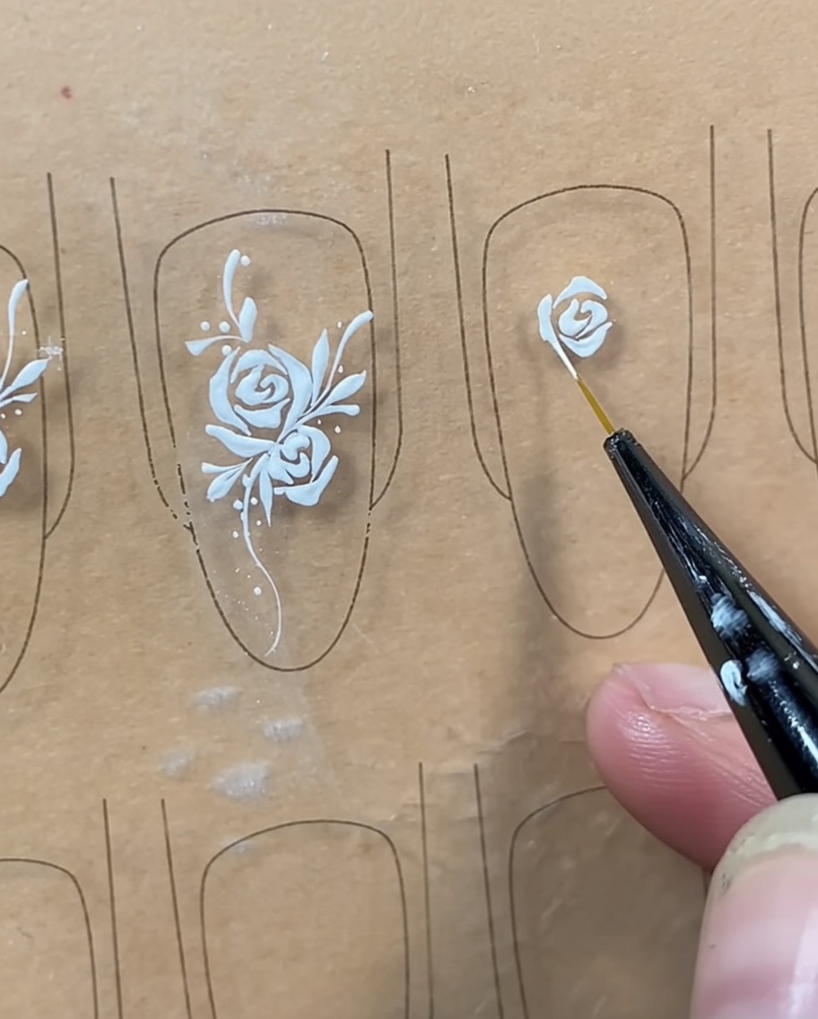 Un pennello liner che aggiunge una linea curva sotto il bocciolo centrale per chiudere la forma della rosa.
