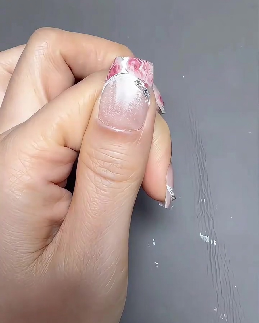 Applicazione di un gel transfer trasparente sulla parte della punta francese dellunghia usando un piccolo pennello di precisione.