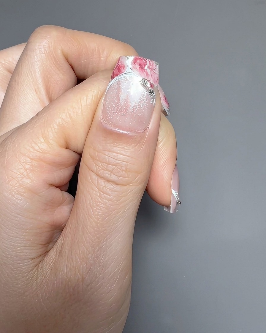 Un primo piano che mostra un secondo adesivo a rosa che viene posizionato con cura sopra il primo su ununghia.