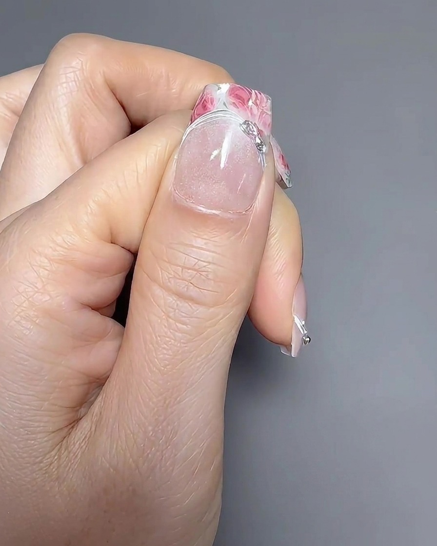 Primo piano di un pennello liner che applica una sottile linea di gel lungo la linea del sorriso di una french manicure.