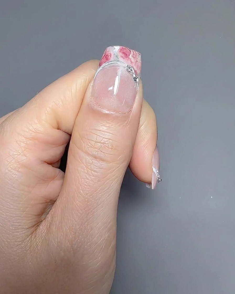 Un pennello a punta sottile che traccia attentamente la linea del sorriso su ununghia con french manicure.
