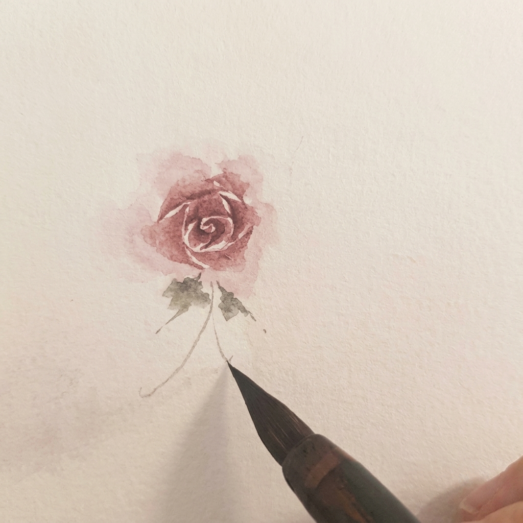 Due piccole foglie verdi ad acquerello dipinte alla base di una rosa finita.