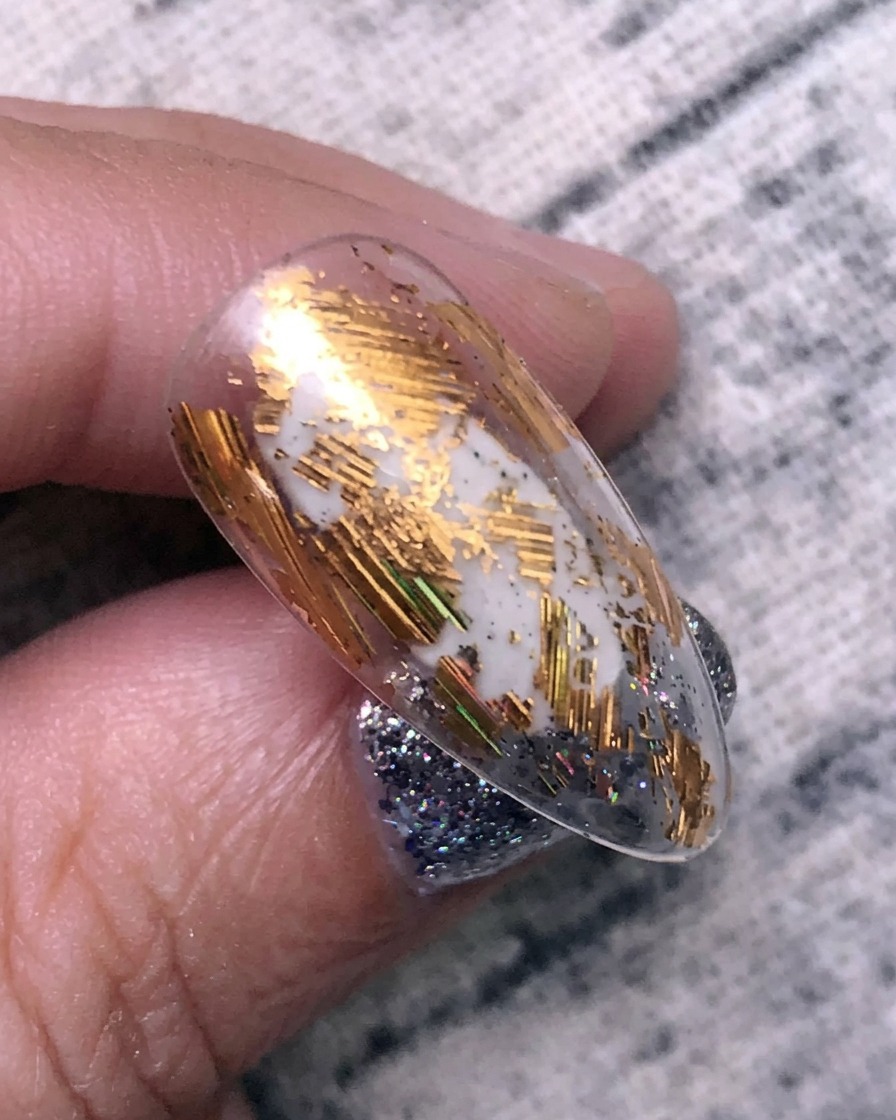 Applicazione di foil di trasferimento oro sulla superficie di ununghia utilizzando uno strumento in silicone.