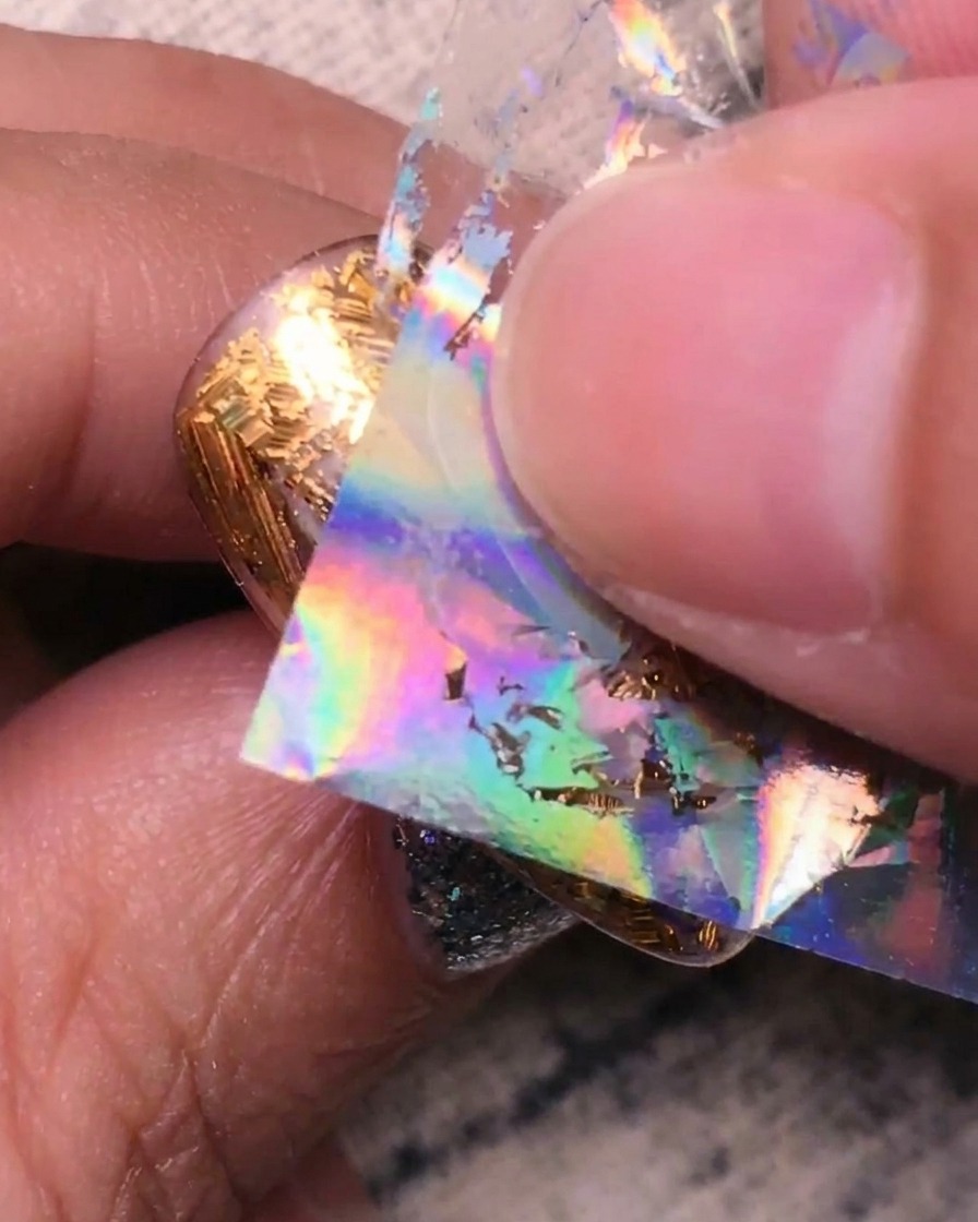 Pressione di foil argento olografico sulle sezioni trasparenti rimanenti dellunghia.