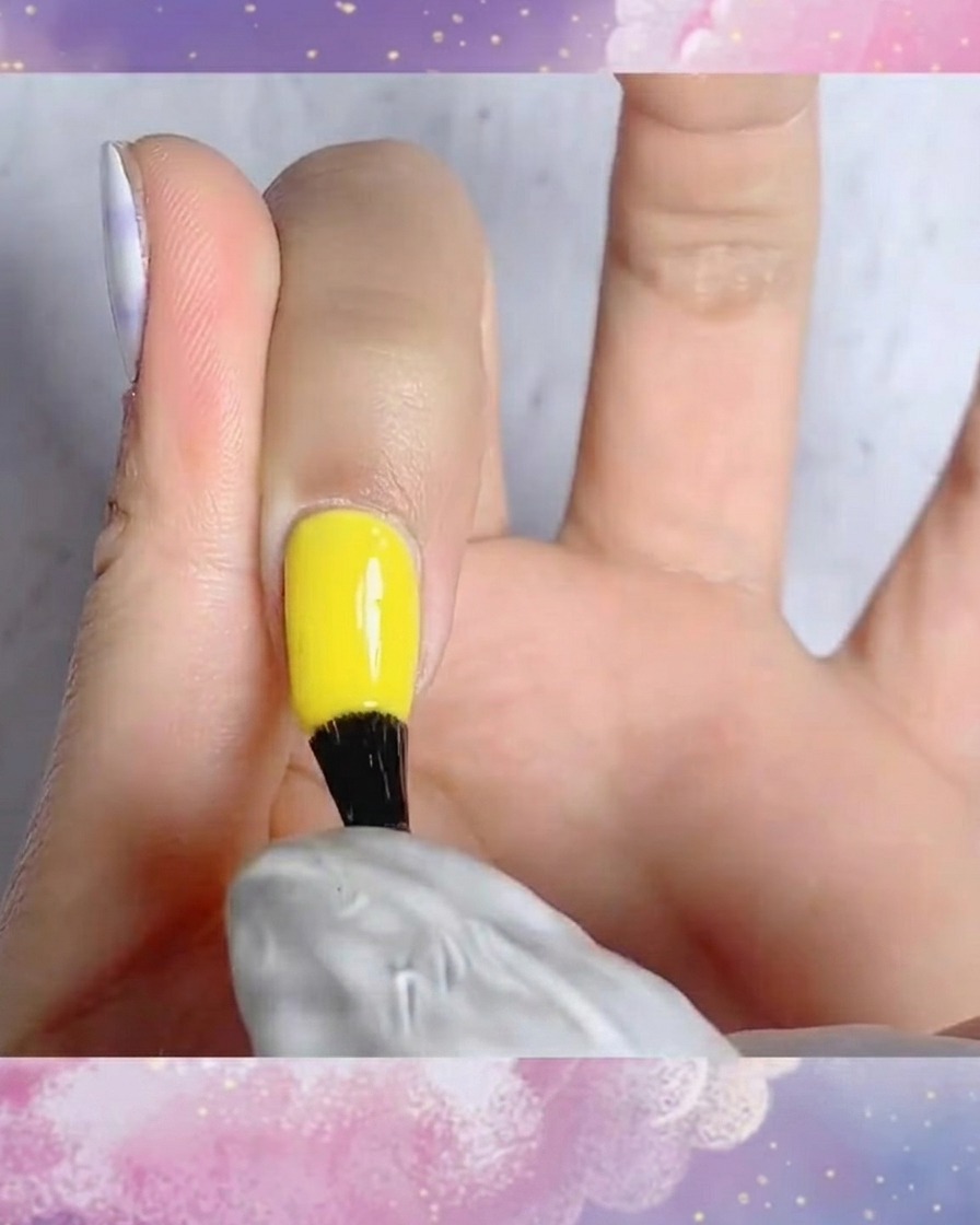 Un pennello che applica il top coat opaco su ununghia con un design tartan blu e bianco dipinto a mano.
