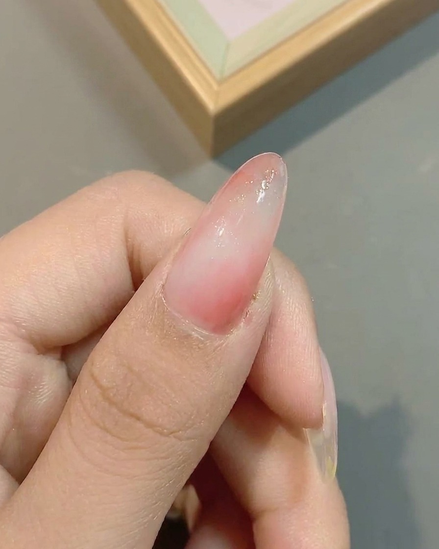 Superficie dellunghia con lapplicazione di glitter effetto nuvola sopra lombré rosa.