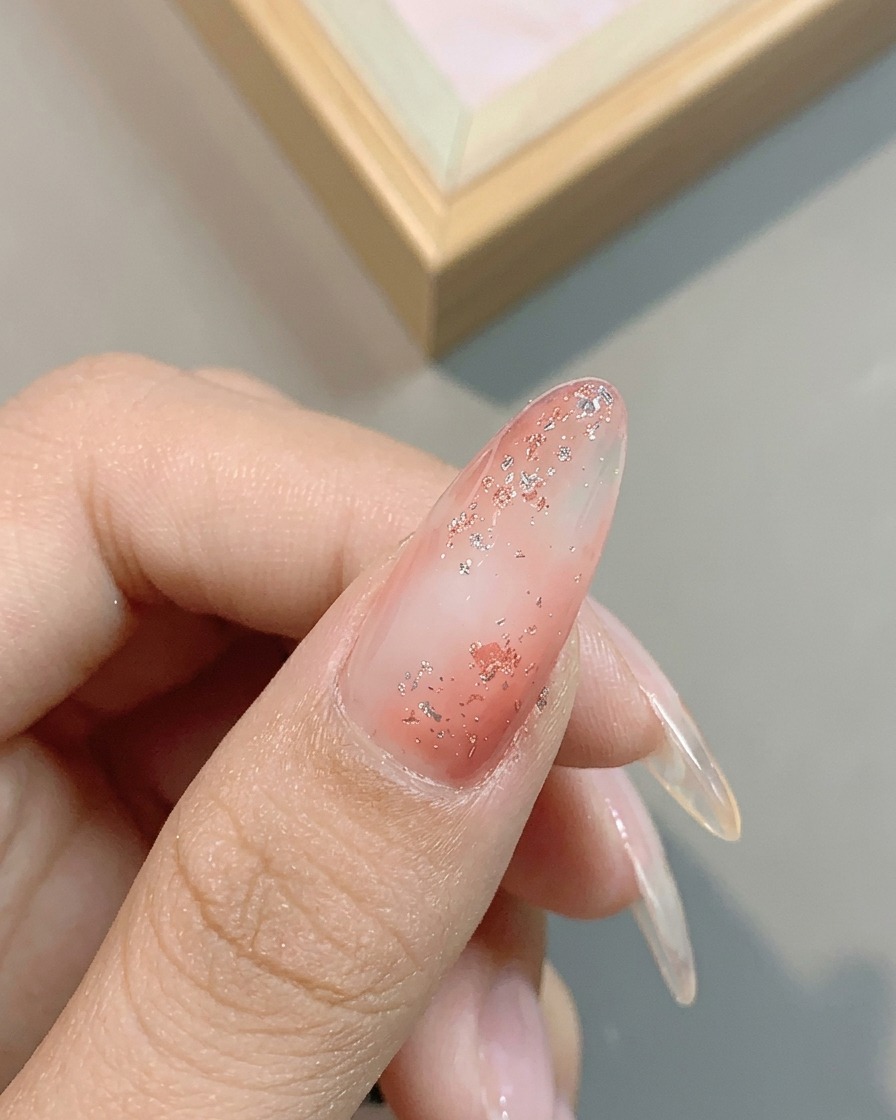 Primo piano del riflesso metallico del gel platino argento n. 04 applicato sopra lunghia glitterata.