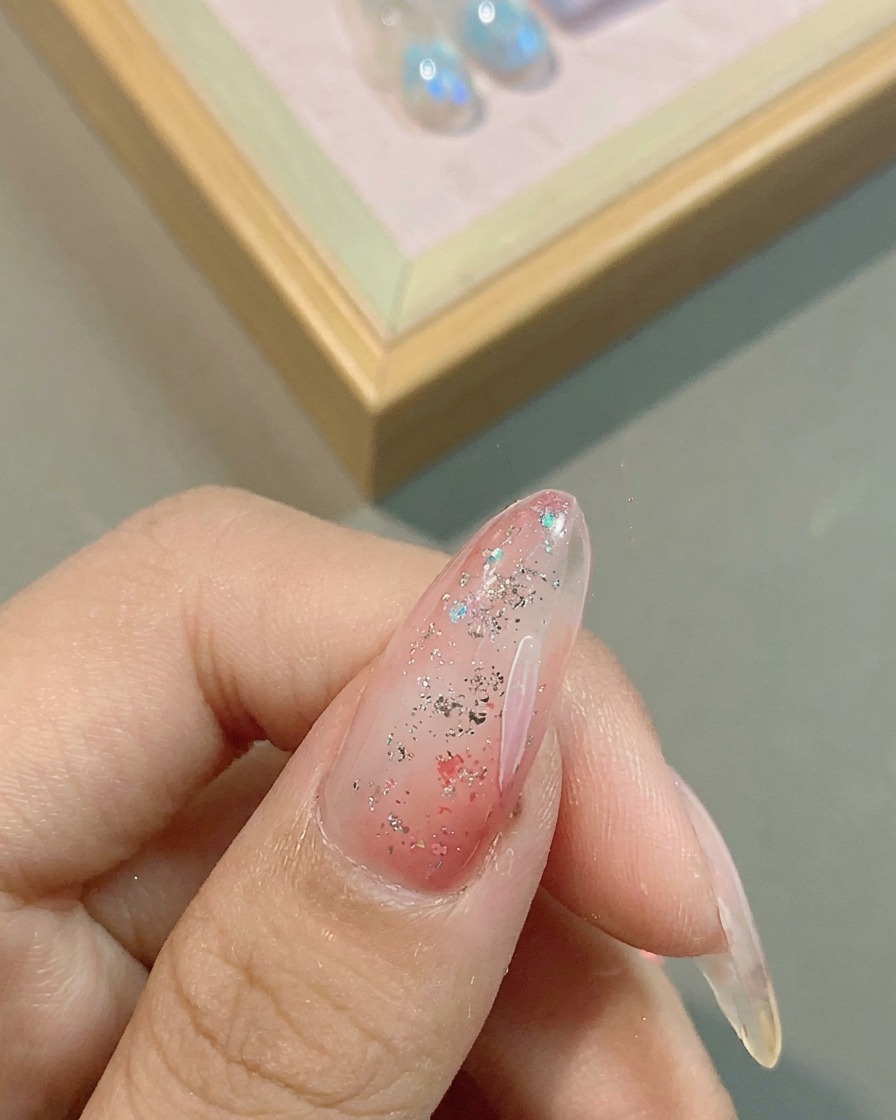 Un pennello liner sottile disegna delicati petali di fiori bianchi su una base rosa glitterata.