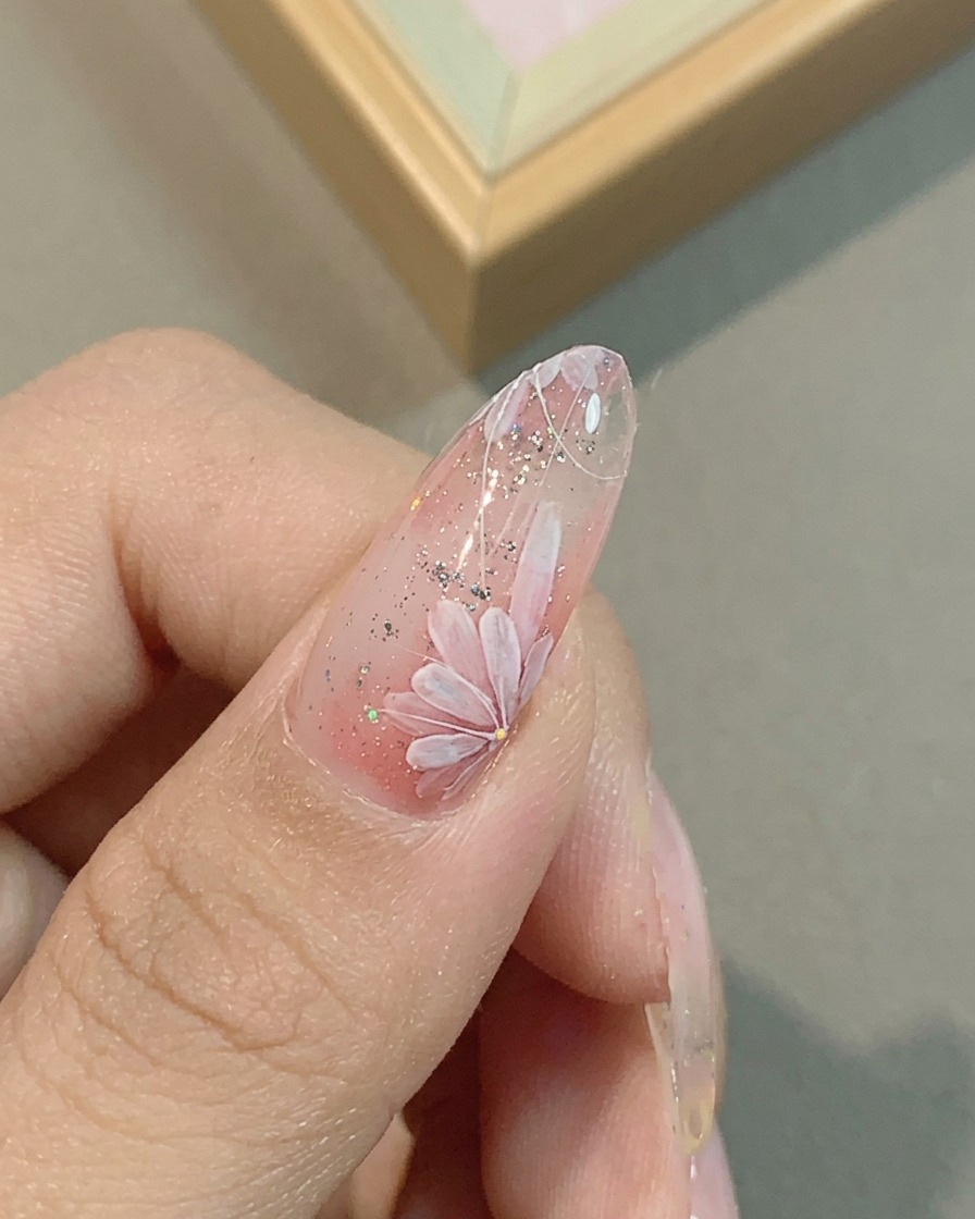 Primo piano di ununghia con petali di margherita rosa rifiniti con un pennello liner sottile.