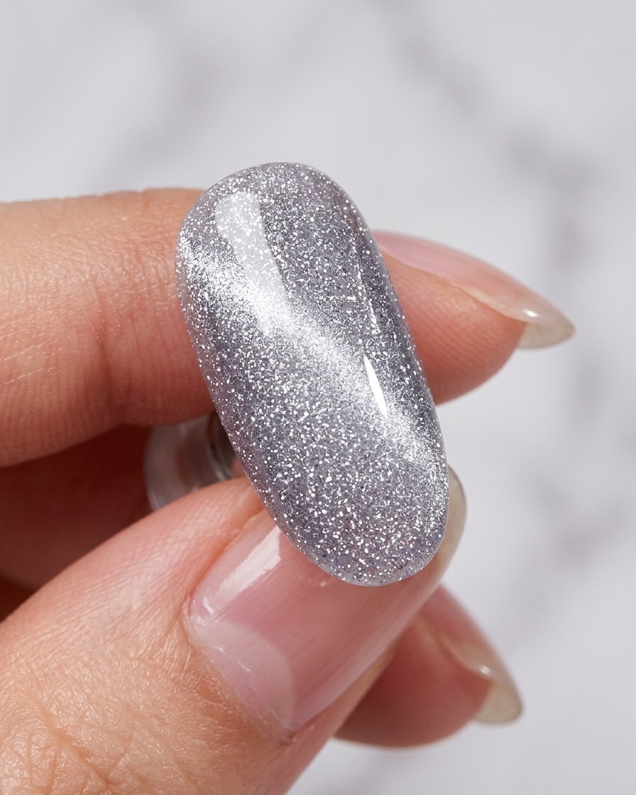 Uno strumento magnetico tenuto vicino a ununghia con gel cat-eye umido per creare una linea luminosa.