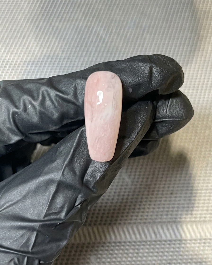 Un primo piano di scaglie di foglia doro pressate sullo strato di dispersione appiccicoso di ununghia.
