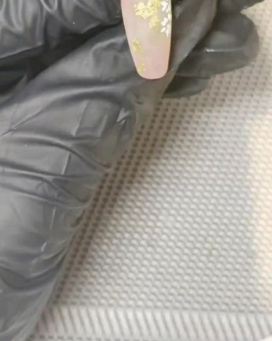 Un piccolo pennello che picchietta del gel giallo nel centro di una margherita bianca dipinta.