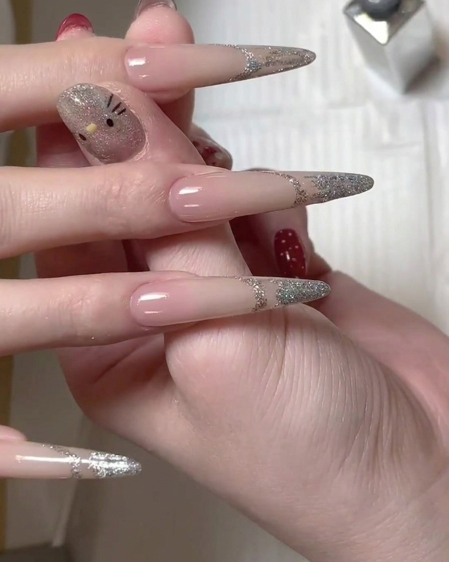 Un pennello applica lo smalto gel glitter argento sulla punta di ununghia lunga per creare il design french.