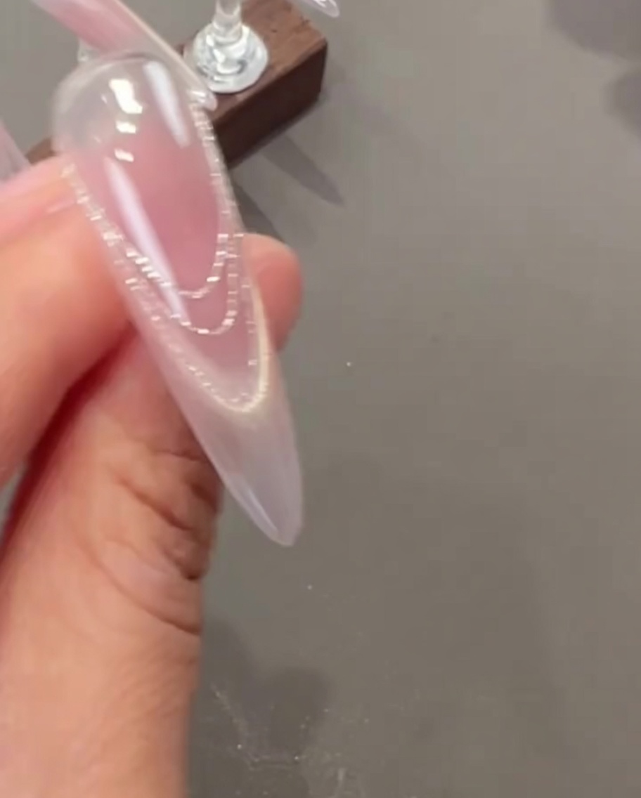 Pinzette che applicano piccoli fiori essiccati delicati e minuscoli charm di perla su ununghia.