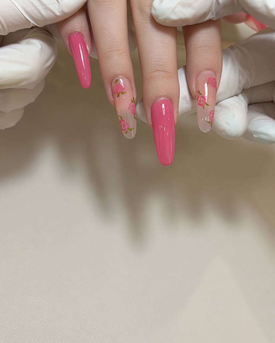 Primo piano di un pennello di precisione che applica gel rosso per creare un piccolo petalo di rosa su ununghia dai toni naturali.