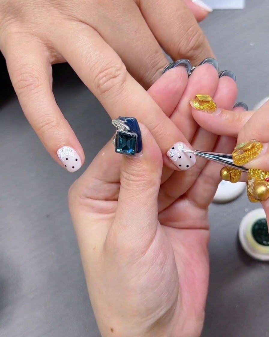 Un top coat lucido viene applicato sopra le unghie con pois neri.