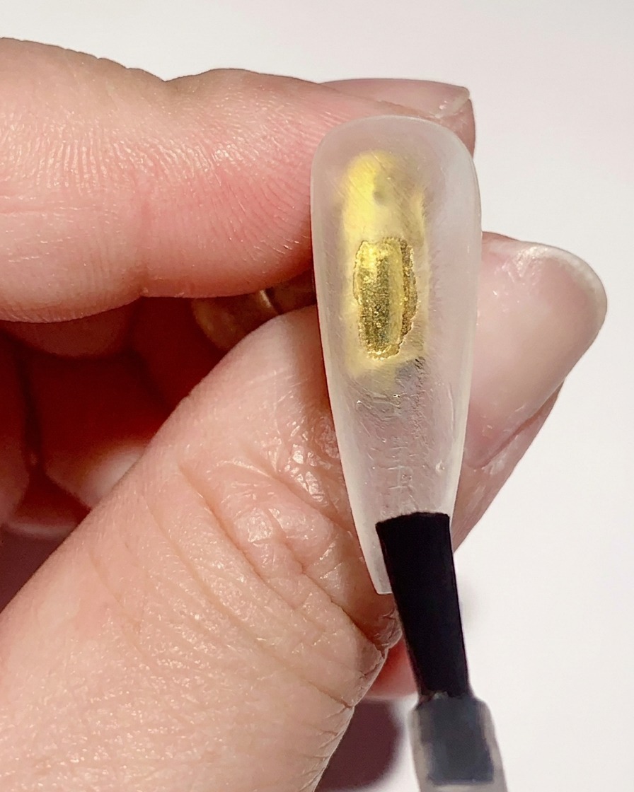 Un pennello applica uno strato sottile di base gel trasparente sulla superficie interna di una tip trasparente.