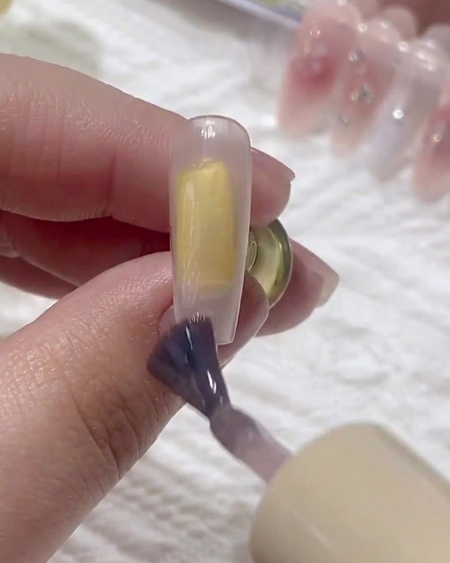 Un pennello applica un secondo strato di base gel sopra quello precedente sullunghia.