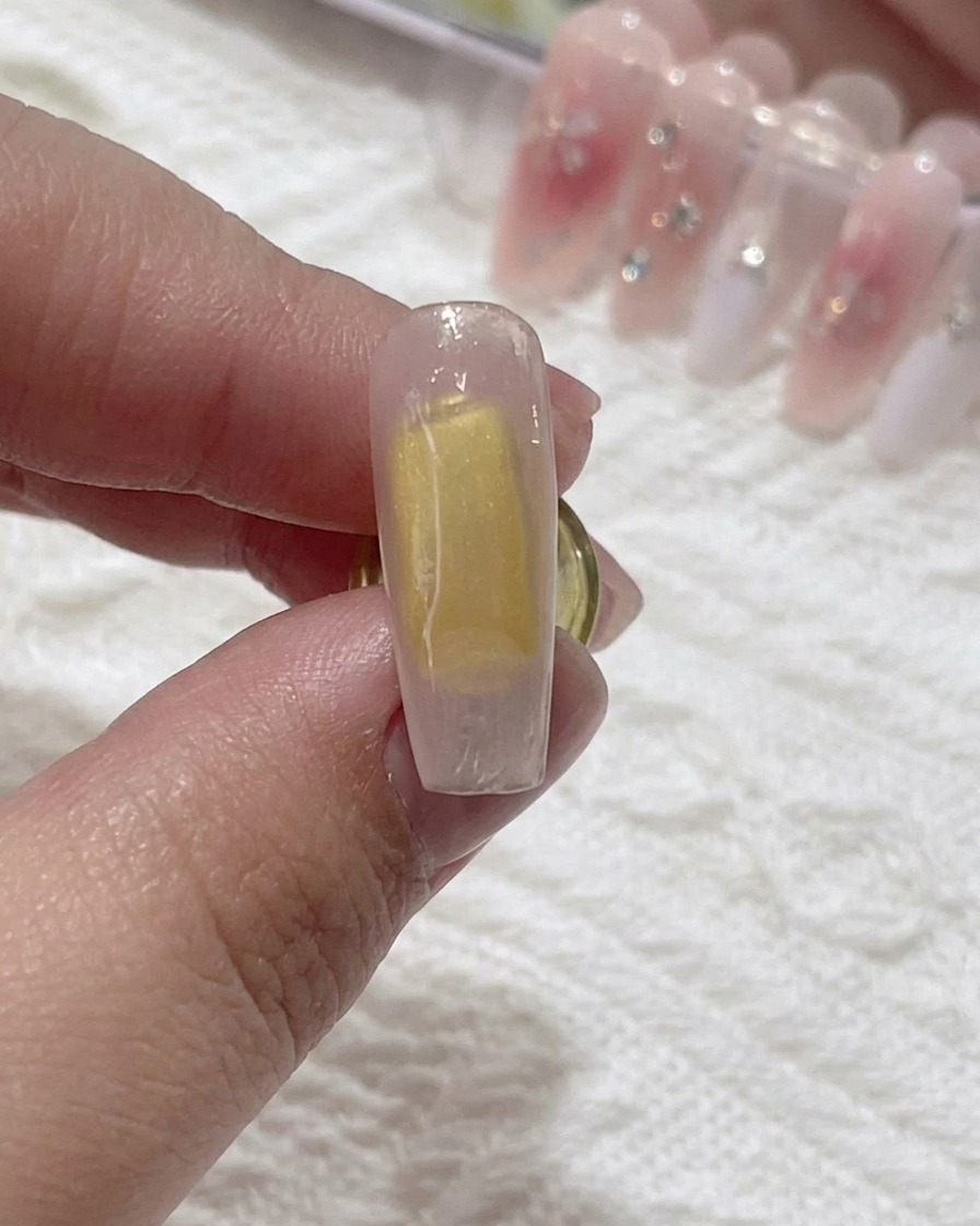 Un pennello applica del blooming gel trasparente sulla superficie dellunghia.