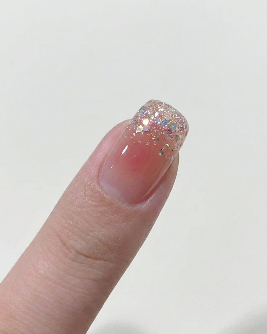 Un pennello che applica uno strato sottile di smalto gel nude su ununghia nuda.