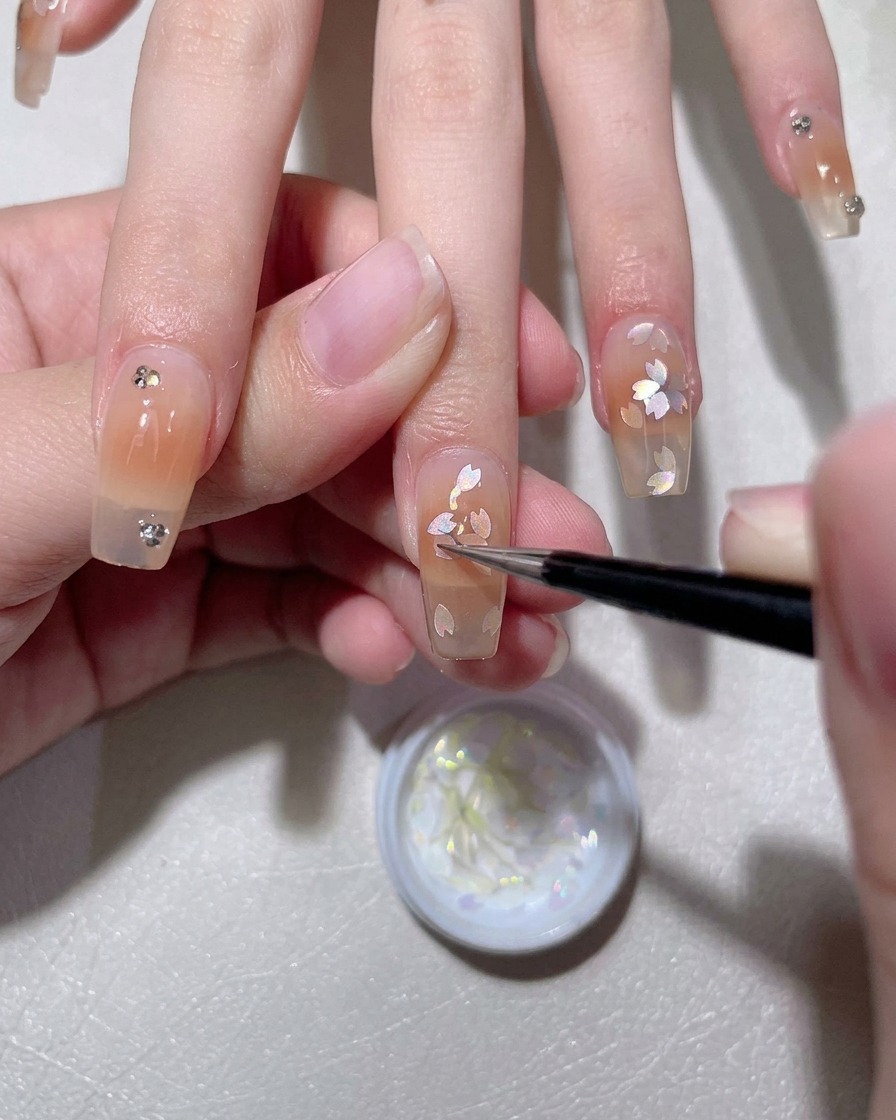 Un pennello applica una base gel bianco latte su ununghia naturale.