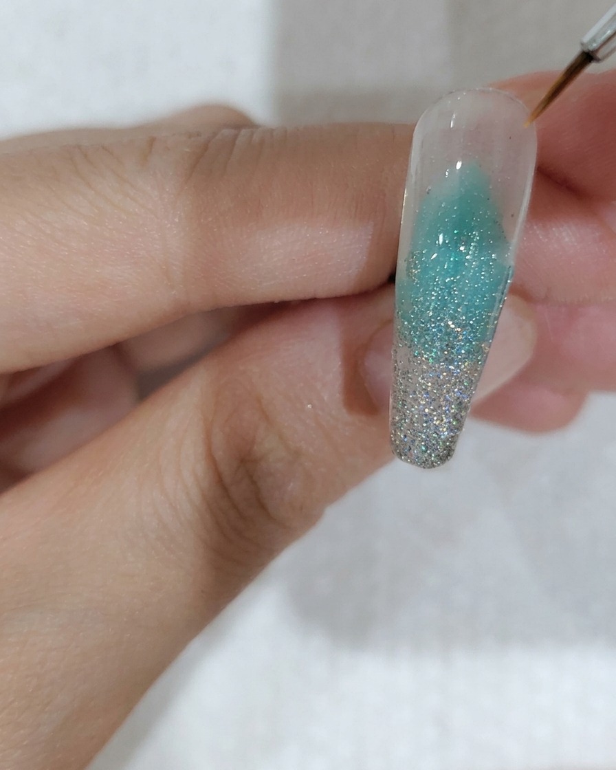 Pinzette che posizionano una singola paillette a forma di fiore di ciliegio sulla superficie dellunghia.