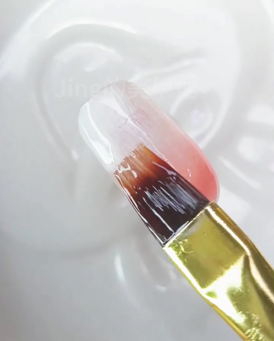 Primo piano di ununghia che mostra una sfumatura liscia e finita dal bianco al pesca-rosa.