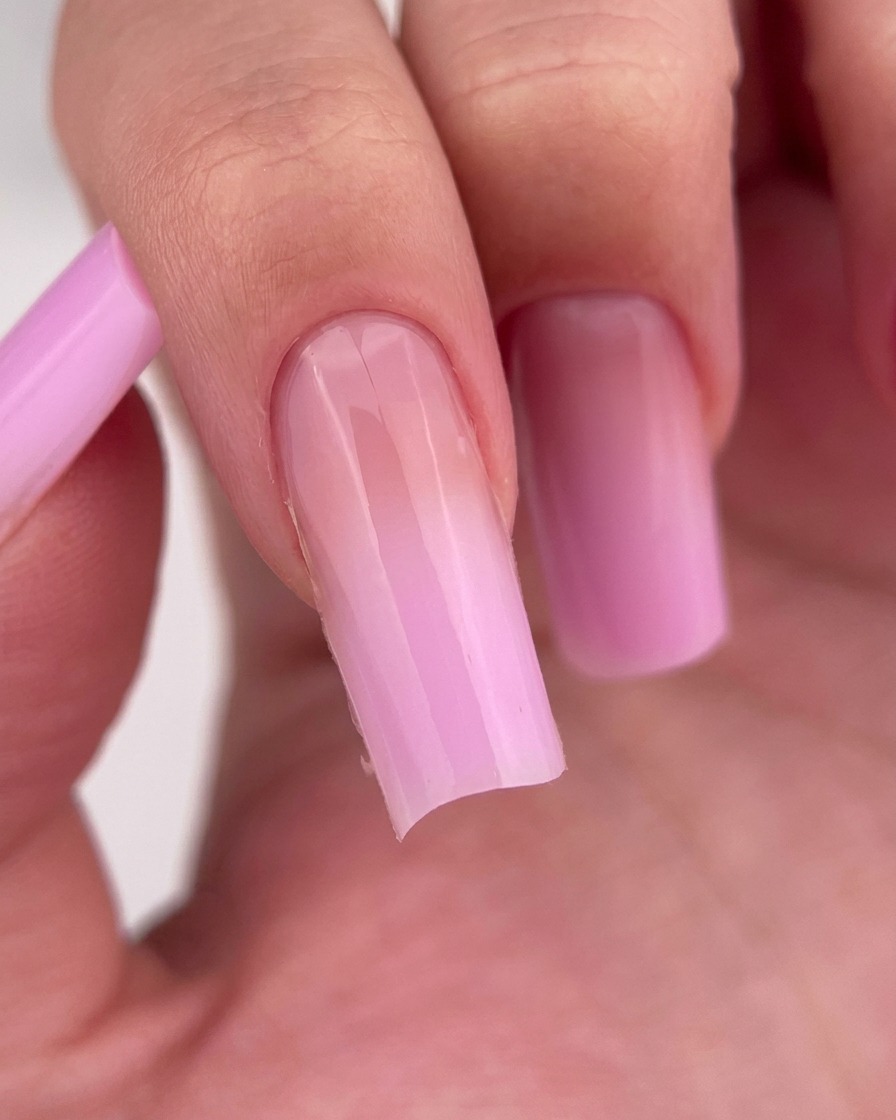 Un primo piano di un dito con uno strato di base coat trasparente e lucido applicato sullunghia.