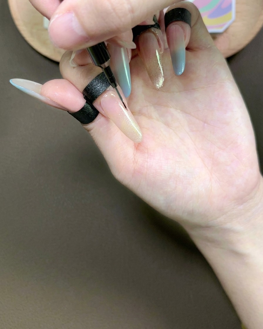 Un pennellino fine trascina delicatamente il gel cat-eye sullindice per creare una sfumatura fluida e affusolata.