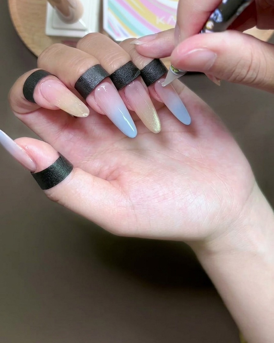 Primo piano di un dotter che applica piccoli punti di adesivo trasparente su ununghia con manicure in gel.