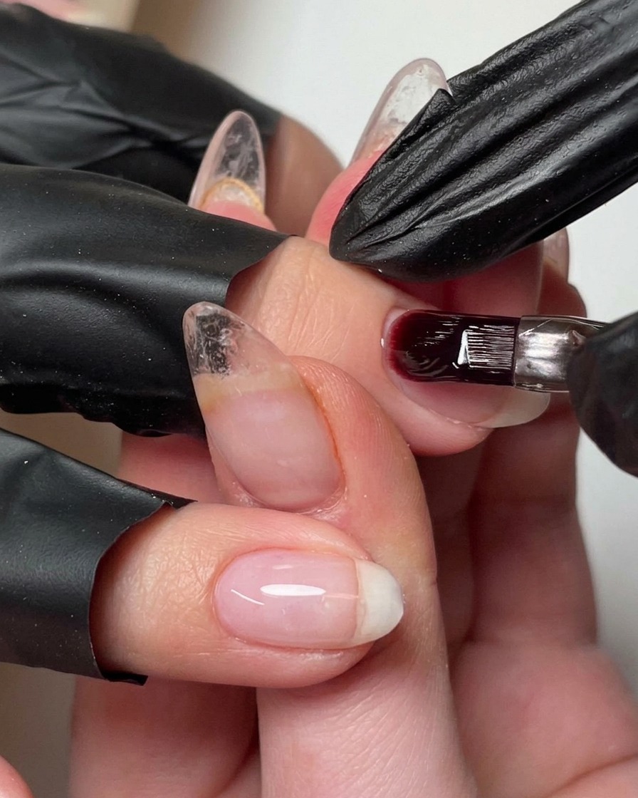 Un pennello che aggiunge una piccola goccia di gel costruttore sullunghia per rifinire lapice.