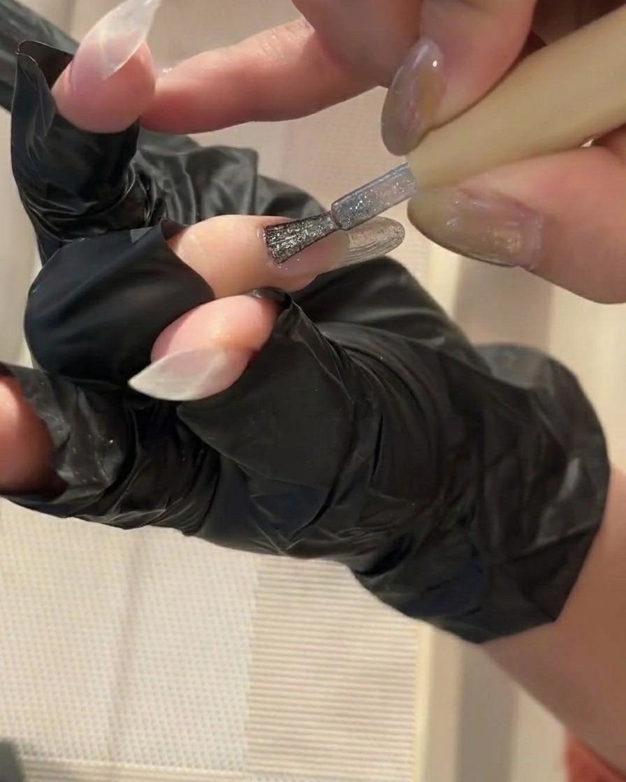 Un pennellino che applica un sottile strato di base gel trasparente su ununghia pulita.