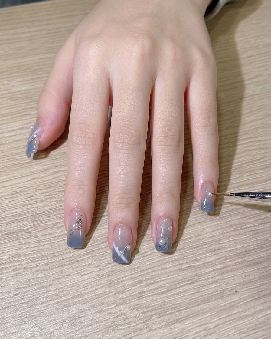 Un pennello che applica un ultimo strato di top coat lucido sul design dellunghia completato.