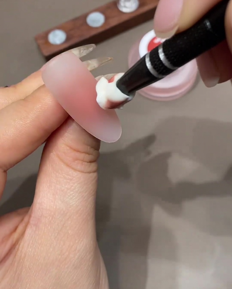 Una spugnetta da trucco che applica uno strato di gel colorato sulla punta dellunghia per intensificare il gradiente ombré.