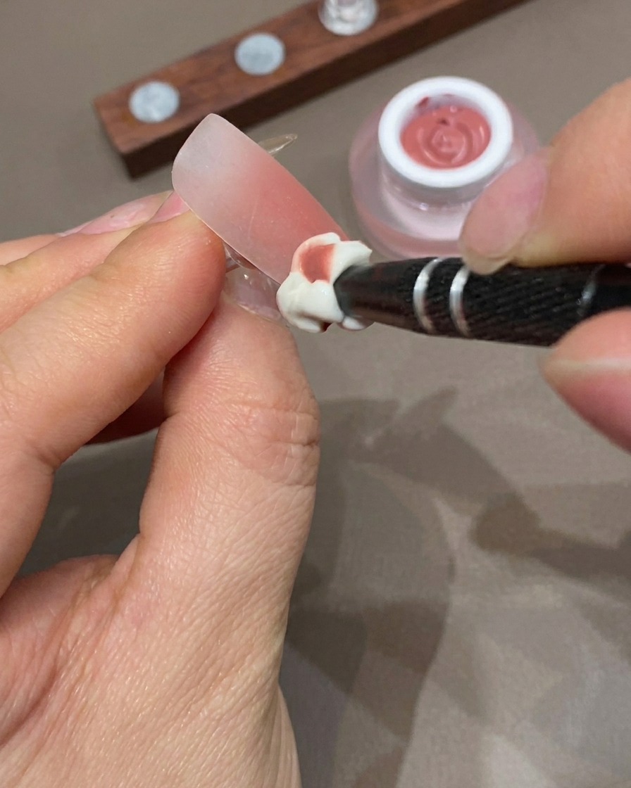 Una mano appoggiata allinterno di una lampada UV per polimerizzare il design ombré delle unghie.