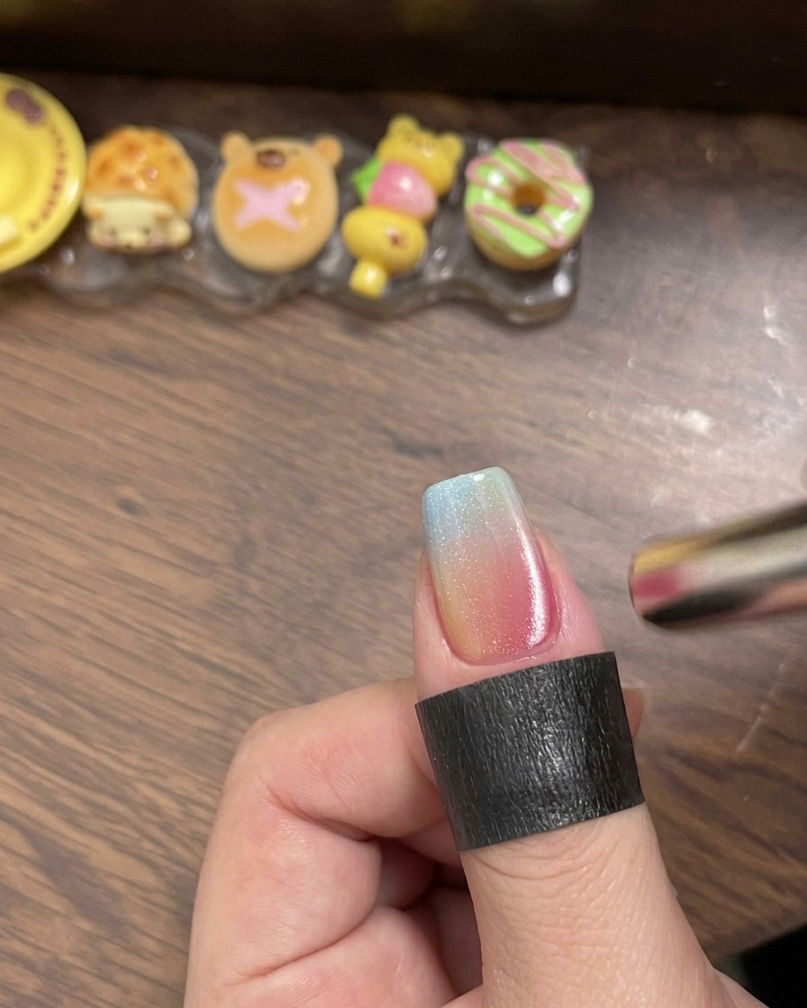 Un pennello che stende un top coat lucido trasparente sopra lunghia gradient multicolore.