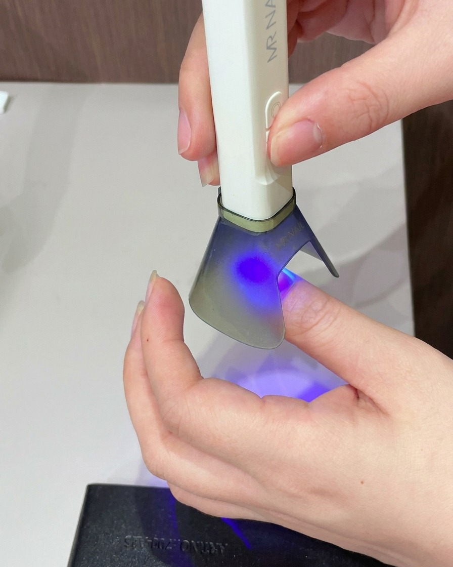 Un pennello che applica uno strato di gel cat eye trasparente su tutta la superficie dellunghia.