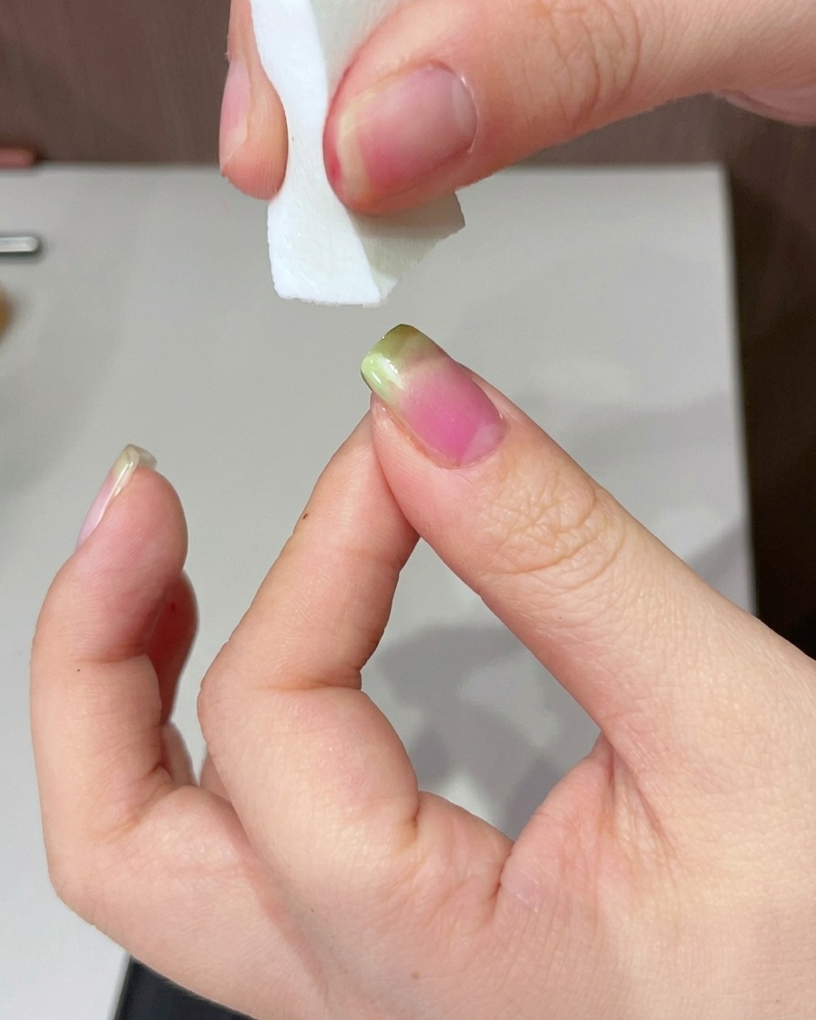 Una mano posizionata sotto una lampada UV per polimerizzare lunghia con la punta verde.