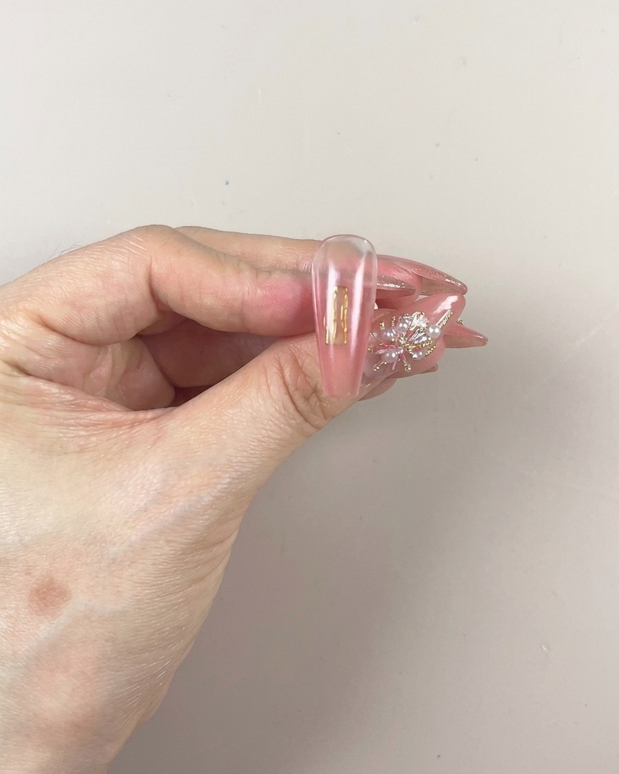 Un pennello applica un nuovo strato di gel pigmentato sulla parte inferiore dellunghia.