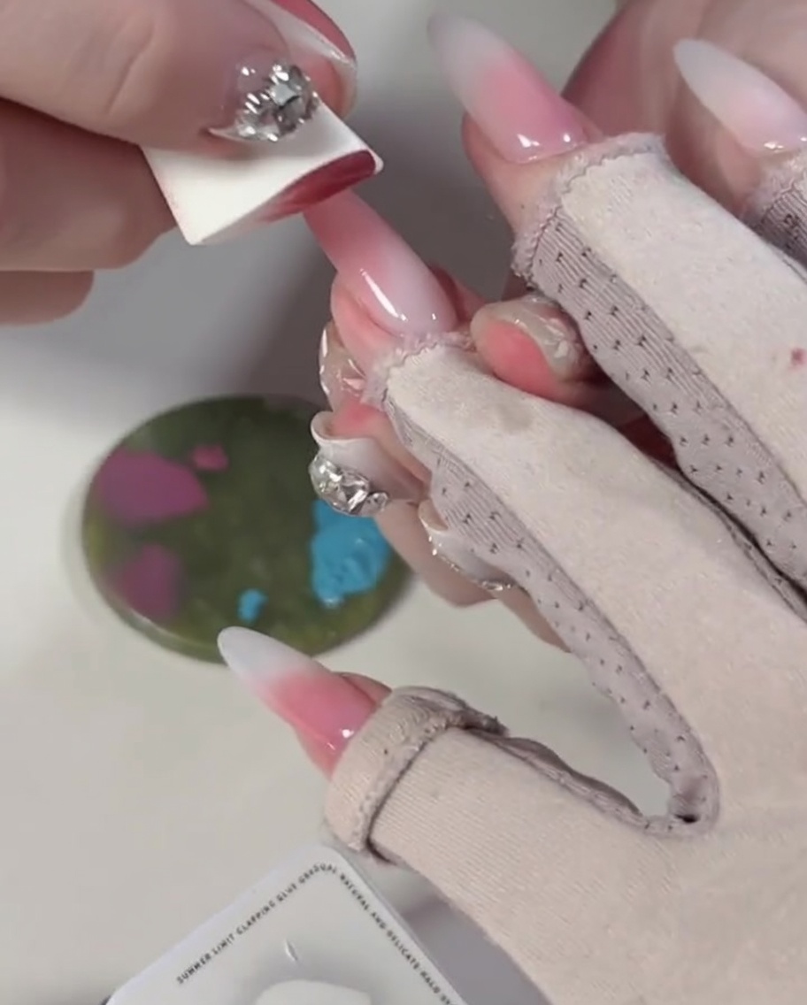 Primo piano di una spugnetta che preme su blocchi di gel blu e rosa su una tavolozza.