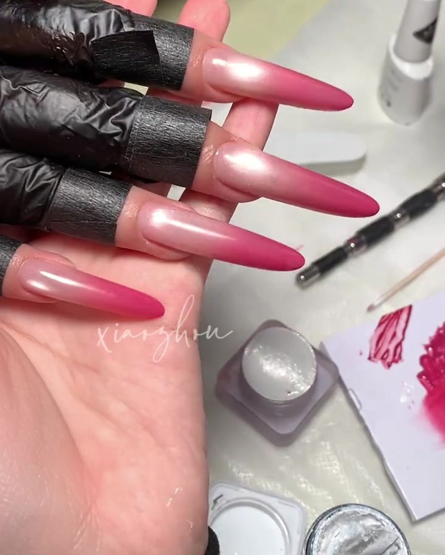 Un pennello che applica un top coat trasparente e lucido su un design di unghie gel magnetiche magenta.