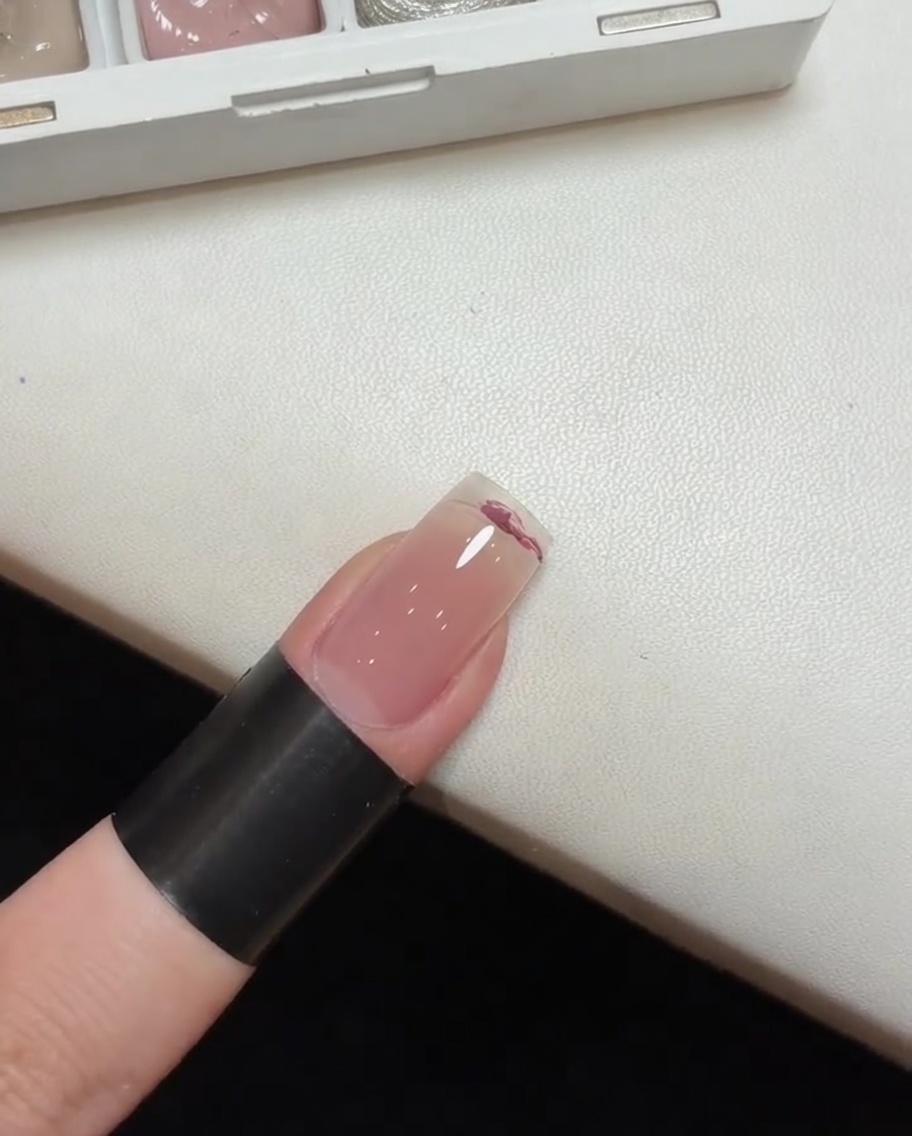 Una spugnetta utilizzata per tamponare e sfumare lo smalto gel rosa su ununghia per creare un effetto degradè.