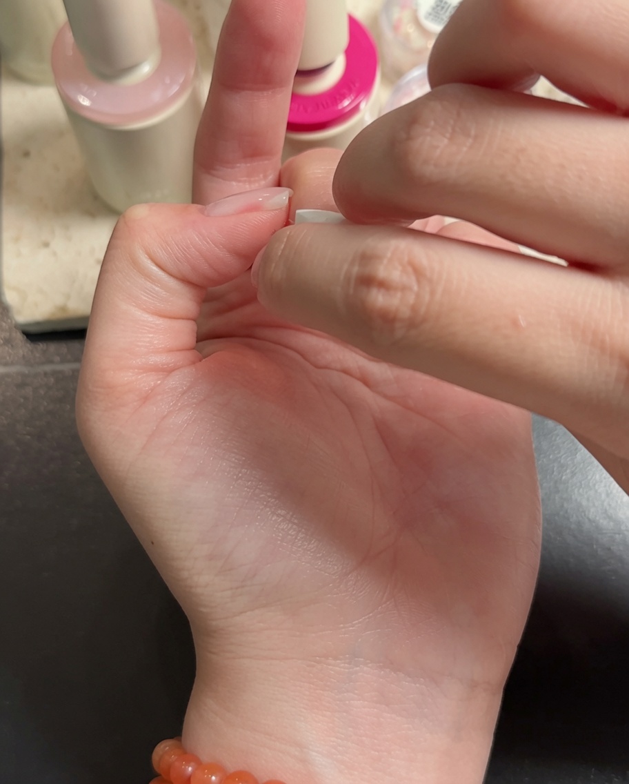 Un pennello per nail art applica il gel bianco sulle punte del medio e dellanulare, creando un effetto sfumato.