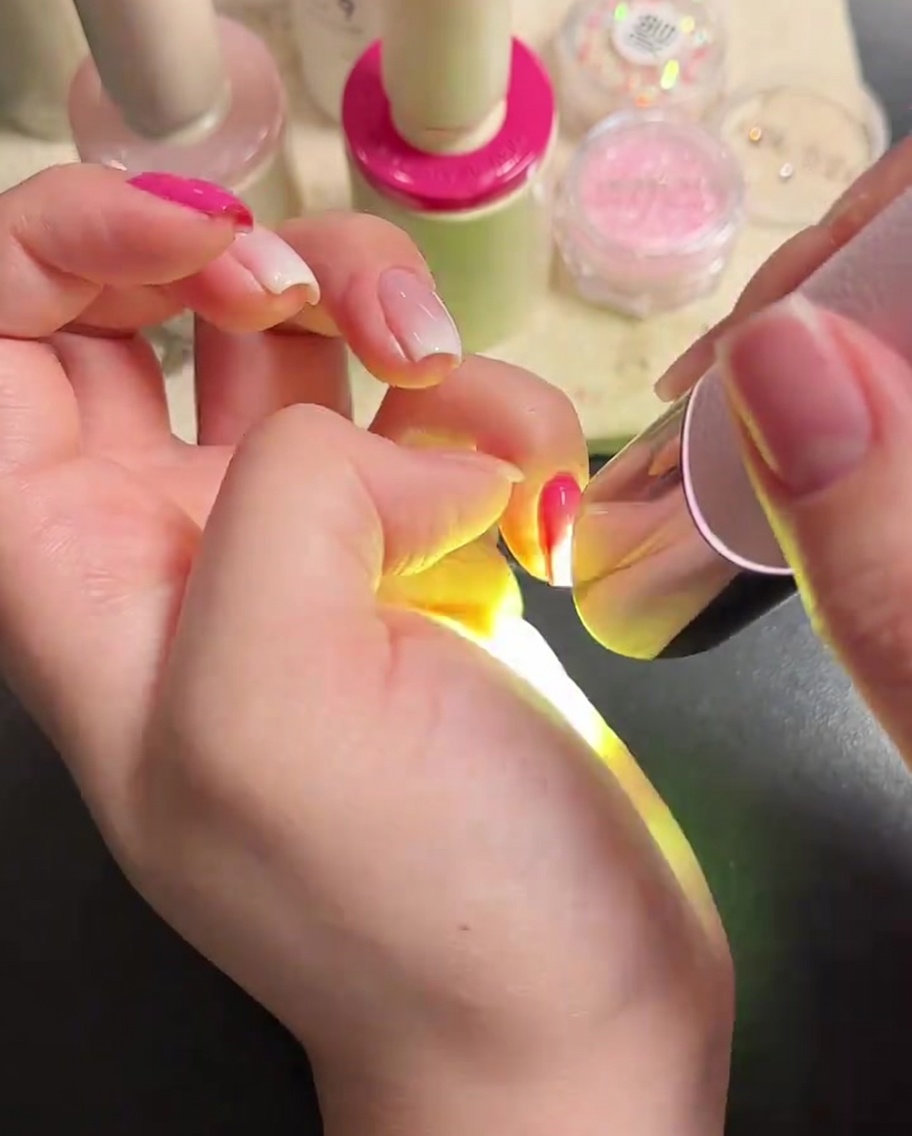 Un pennello per unghie applica un top coat trasparente e lucido sulle unghie curate.