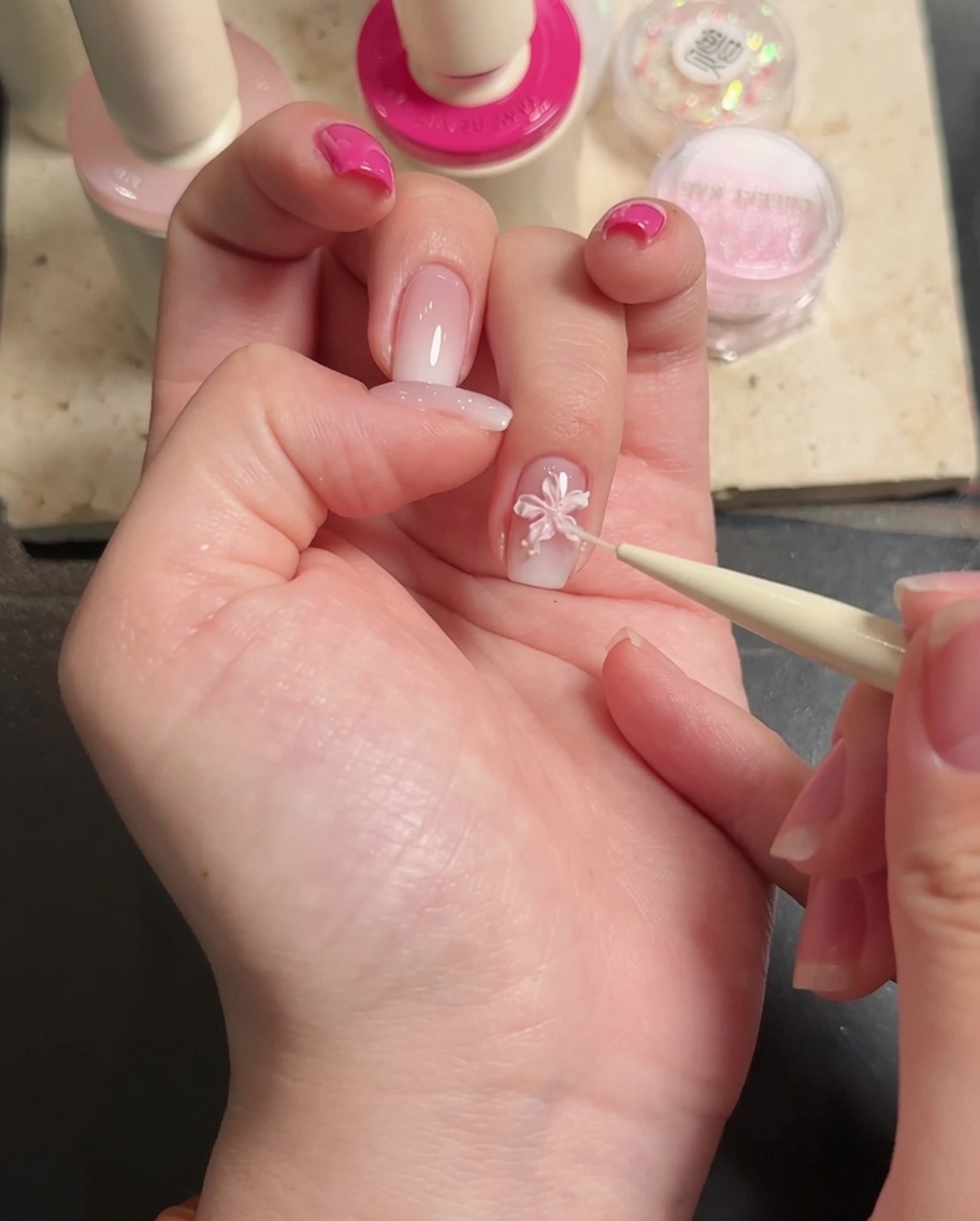 Primo piano di pinzette che posizionano un piccolo strass decorativo al centro di un fiore 3D bianco.